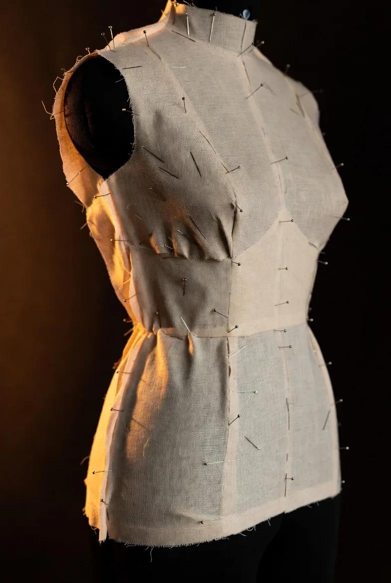 Toile su manichino con spilli durante sessione di fitting in atelier